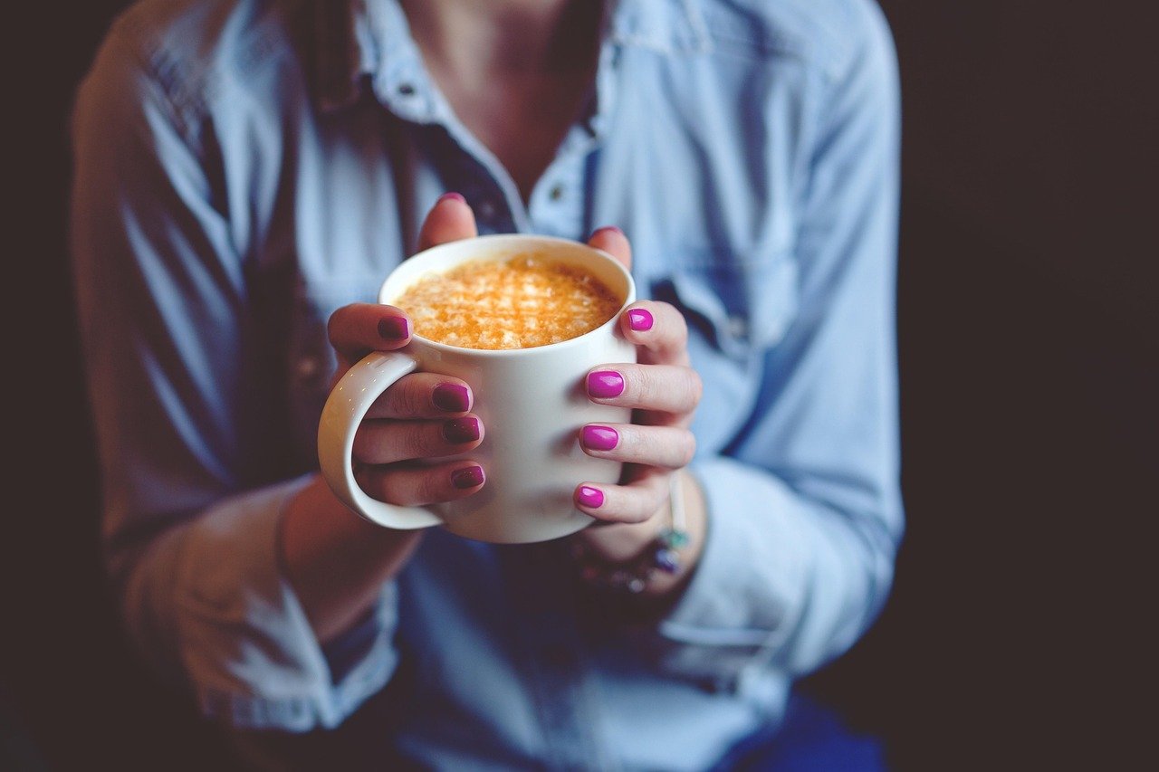 Close up image of a person holding a cup of coffee in their hands.