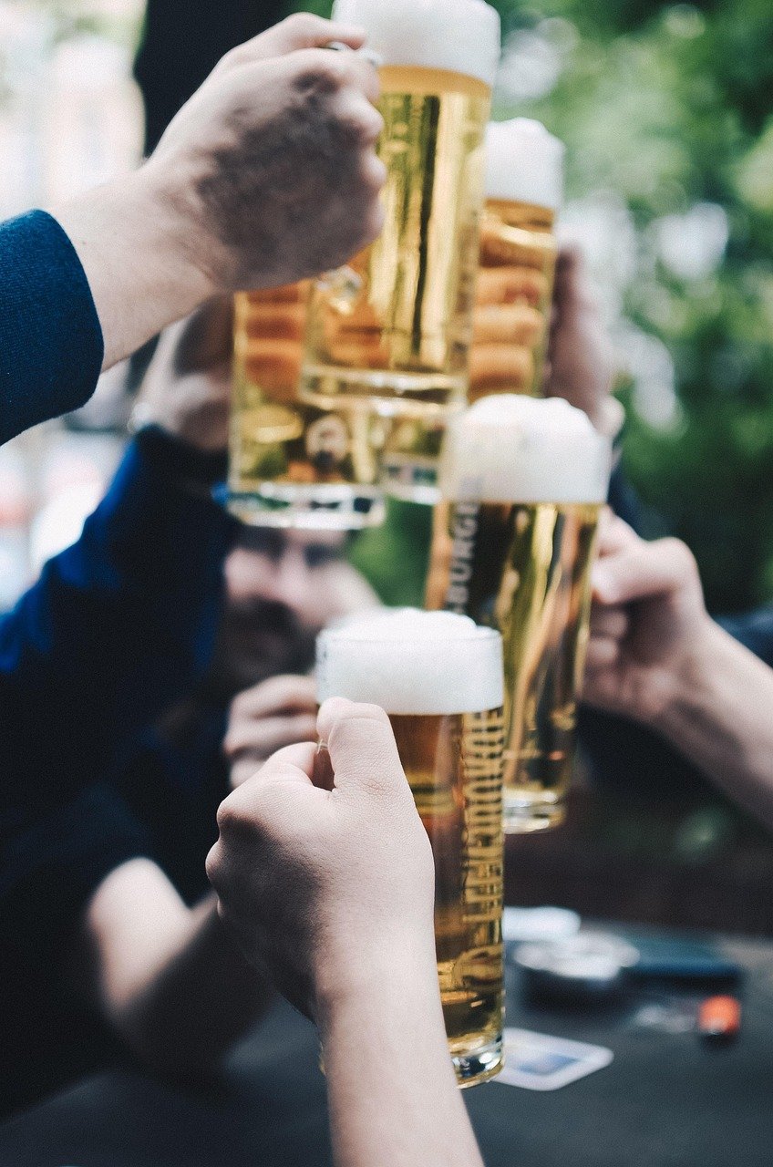 A close up of hands of friends' hands holding beer steins and making a toast.